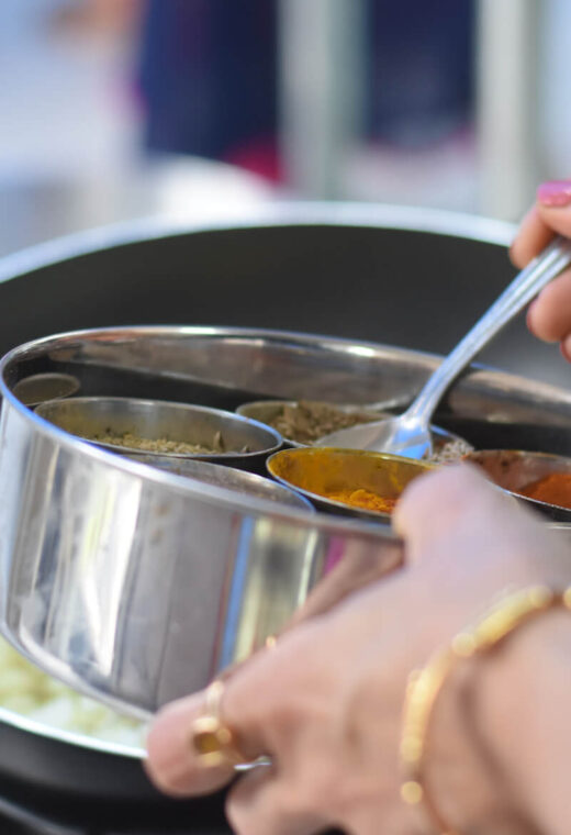 an up close image of someone cooking a meal - using a spoon to add spices to a dish