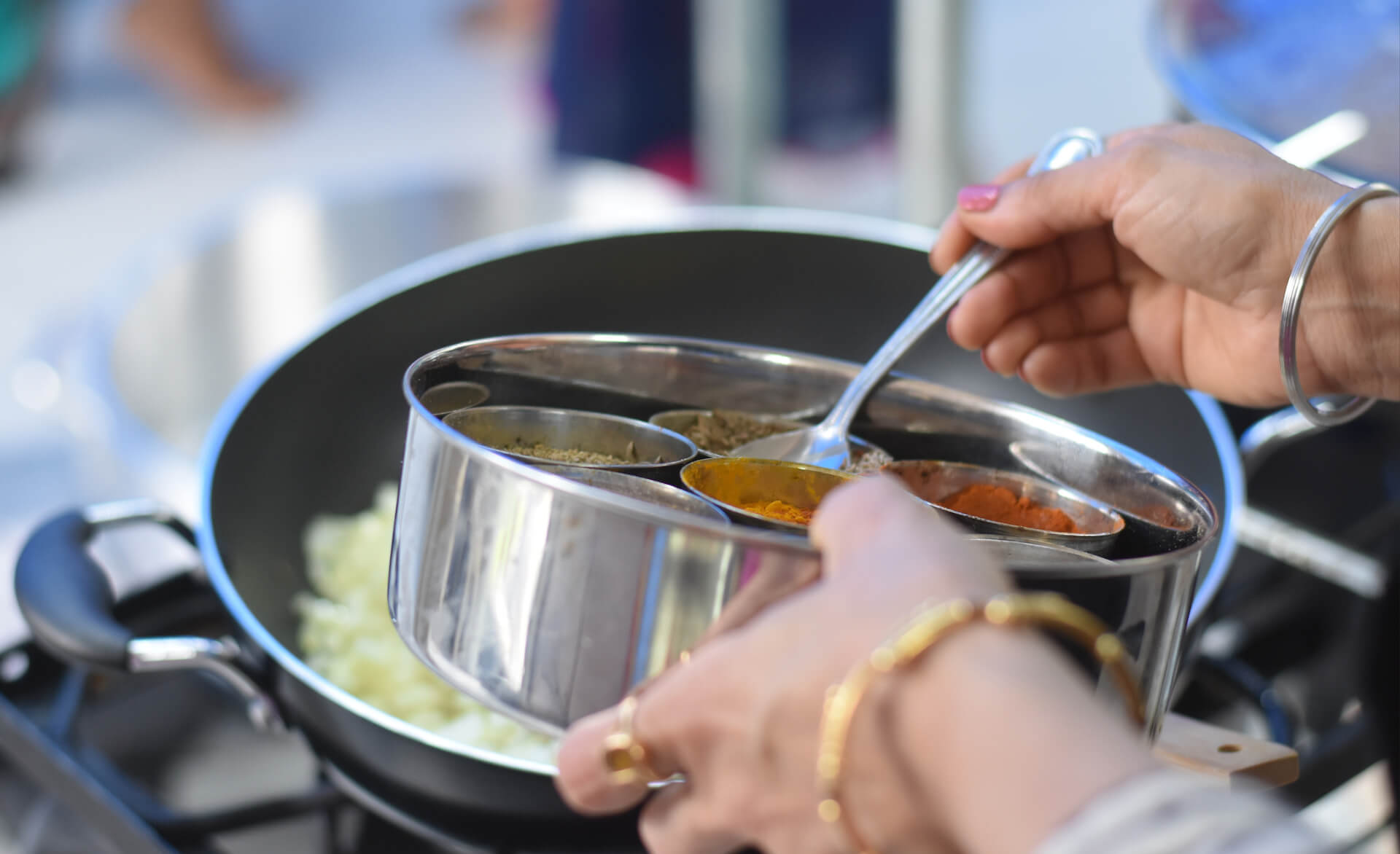 an up close image of someone cooking a meal - using a spoon to add spices to a dish