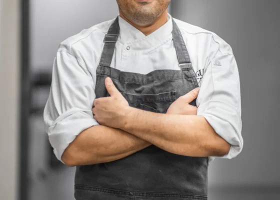 image of a man in chefs apron crossing his arms facing the camera
