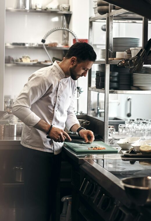 a chef cutting food in their kitchen. a way to cut the food could be considered kitchen hacks
