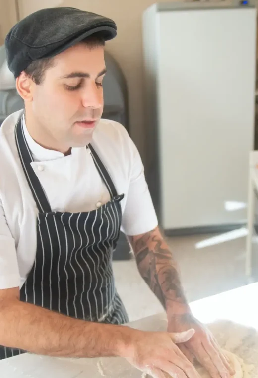 a man wearing a white chef top and a blue apron is preparing food.