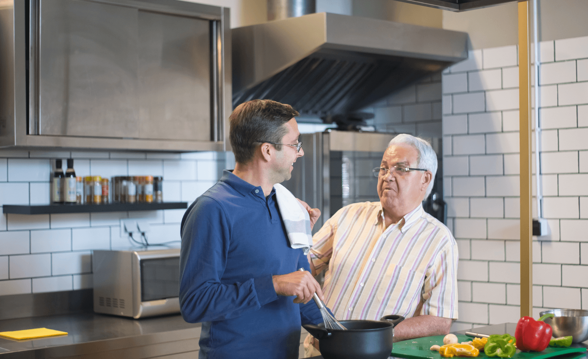 2 men cooking together, they are smiling and enjoying themselves