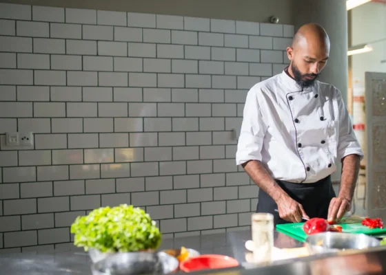 man in chef whites chopping some vegetables