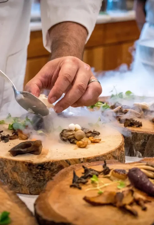 Someone serving food on a large wooden slab.