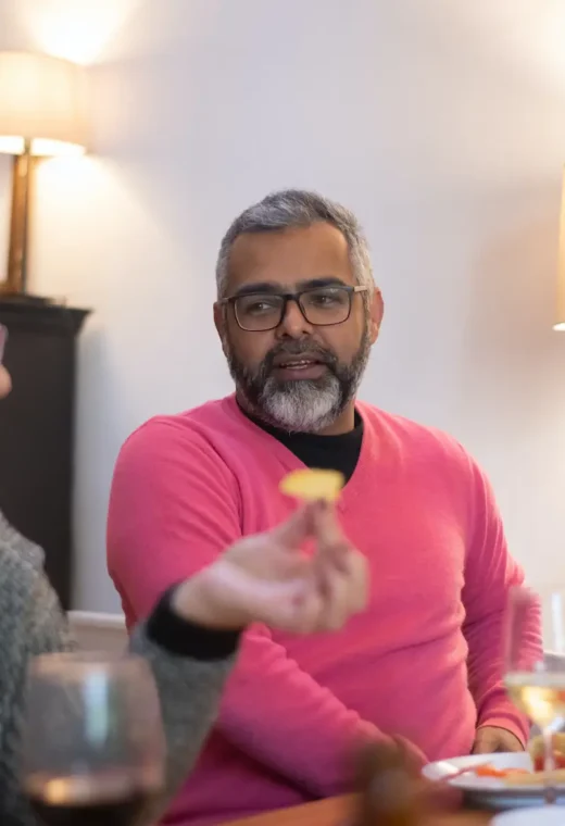a man and woman sat at a table eating food with glasses of wine