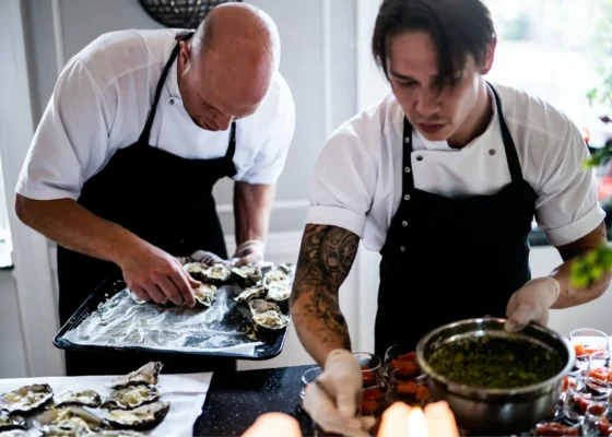 two caterers working on a meal, dishing it up on to trays