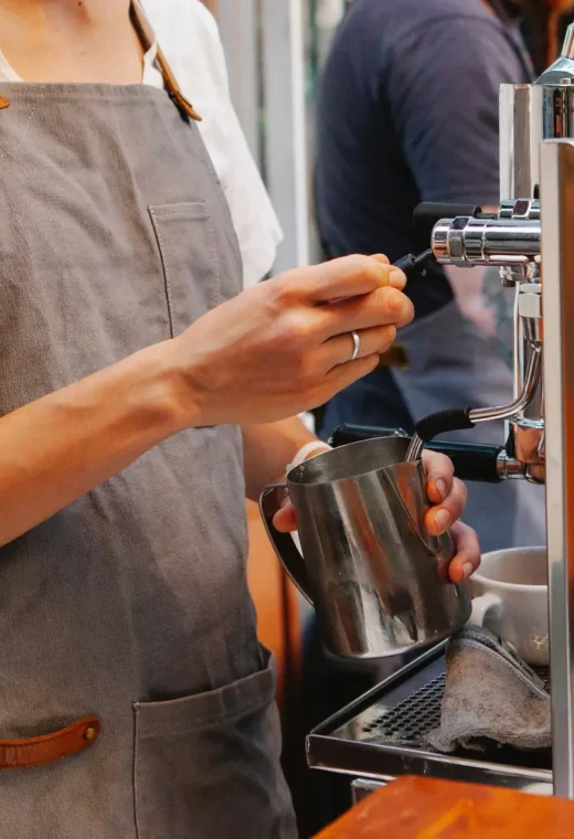 person wearing a grey apron is measuring an ingredient