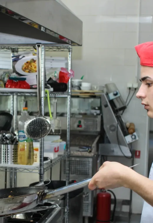 man in a red hat cooking over a stove